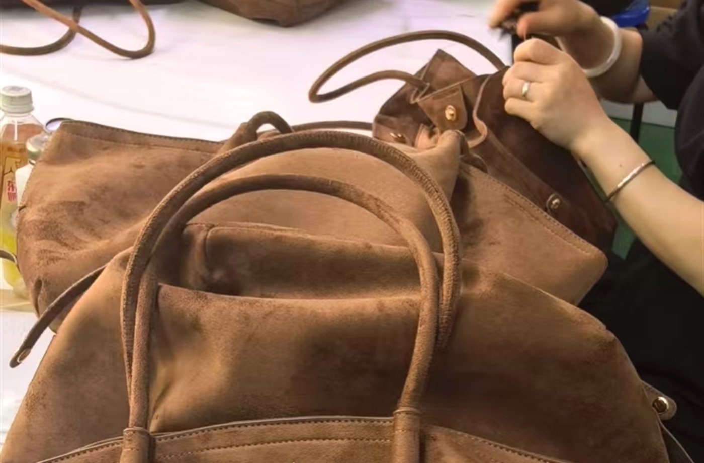 Workers assembling handbags on a factory work table